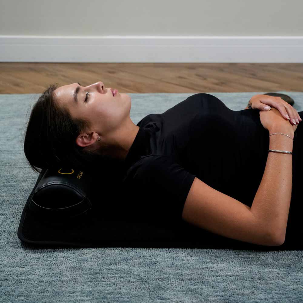 Lady laying on CELLER8 full body PEMF mat using neck pillow