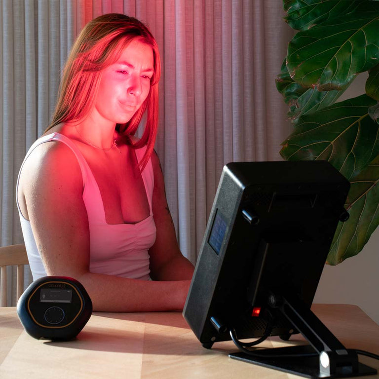 Woman using a red light therapy device on her face with CELLER8 in front