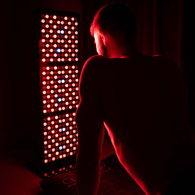 Man doing upward facing dog on CELLER8 full body mat in front of half body red light panel