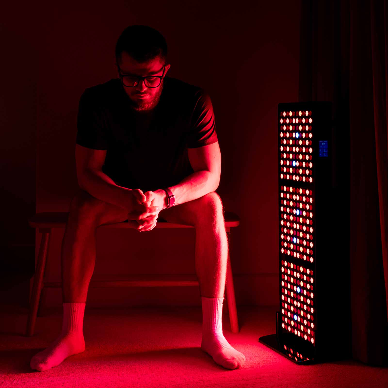 Man sitting to the side of the CELLER8 half body red light panel