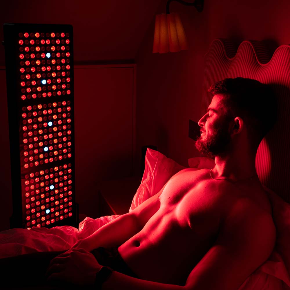 Man sat in bed using CELLER8 half body red light panel