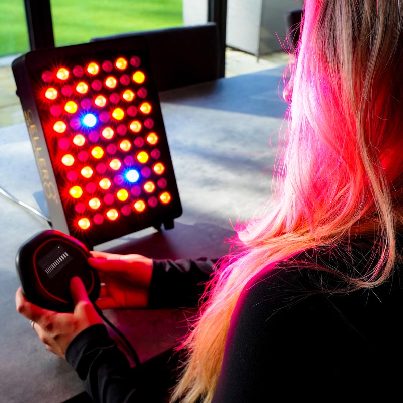 Women adjusting CELLER8 while using desktop red light panel 