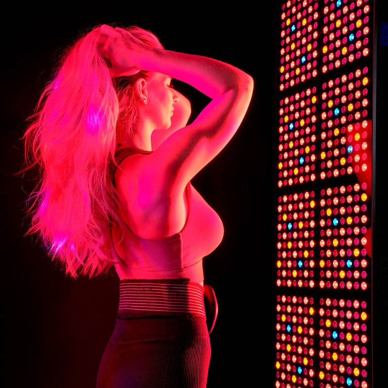 Lady stood in front of CELLER8 full body red light panel with CELLER8 PEMF around waist