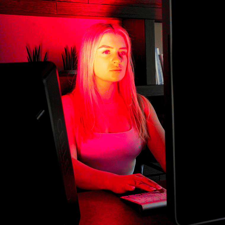 Person sitting at a computer with CELLER8 red light panel 