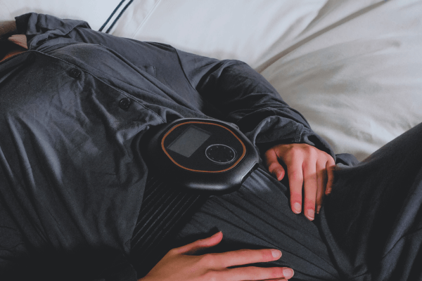 Women laying in bed with CELLER8 PEMF device strapped on to her waist