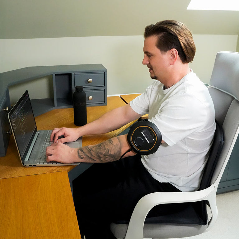 Man sitting on travel mat with CELLER8 on arm while typing on a computer