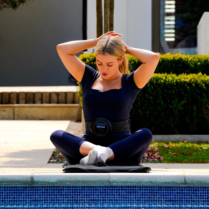 Women with CELLER8 Strapped on her waist, sitting on the CELLER8 full-body mat relaxing.